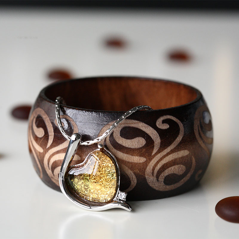 Elegantný náramok striebornej farby vykladaný skleneným príveskom